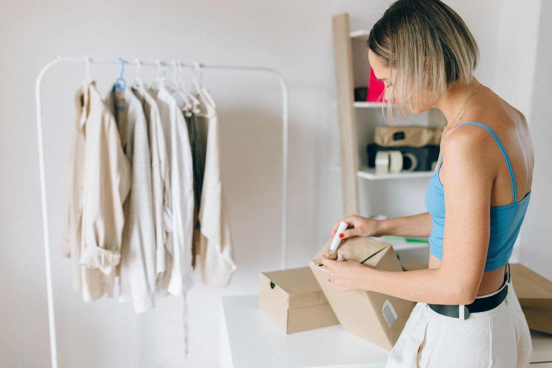 A small-business owner packing a clothing order into a box.
