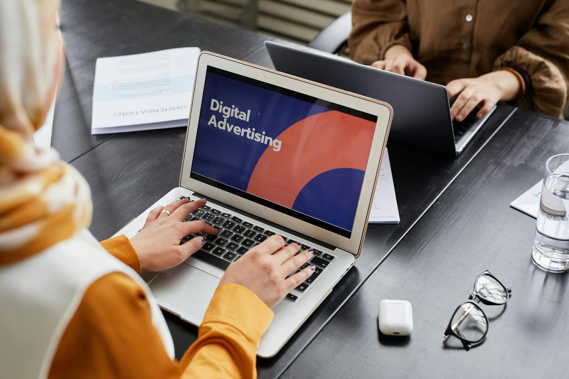 Two marketers reviewing digital advertising on laptops in an office.